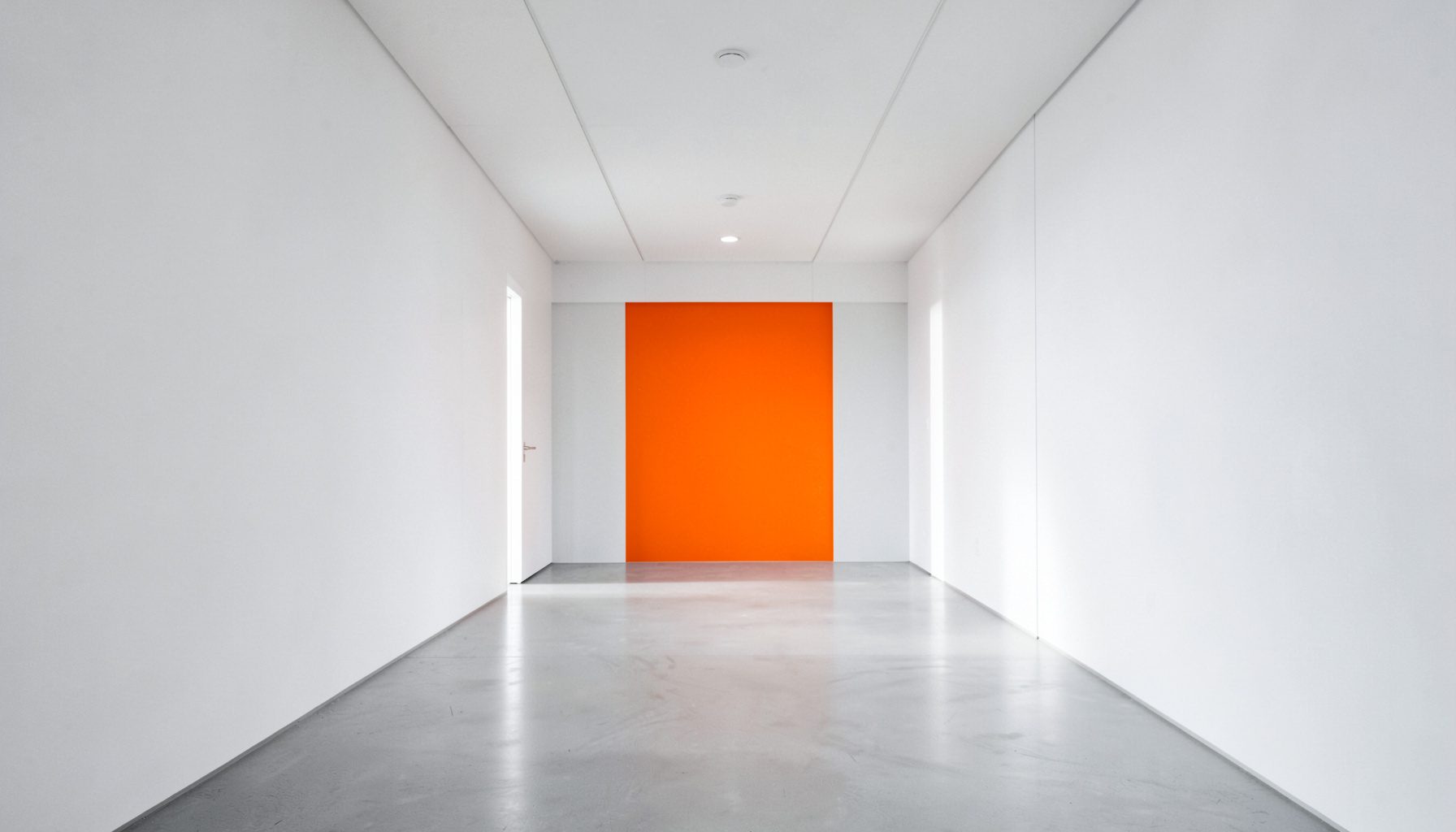 Vue symétrique d'un couloir de laboratoire moderne aux murs blancs, éclairé par une lumière naturelle douce, dans des tons neutres et apaisants